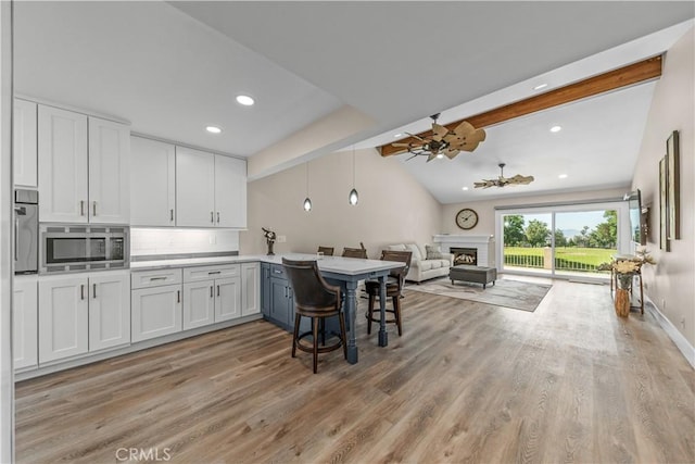kitchen with appliances with stainless steel finishes, open floor plan, a ceiling fan, light wood-type flooring, and recessed lighting