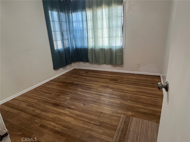 unfurnished room featuring wood finished floors, baseboards, and plenty of natural light