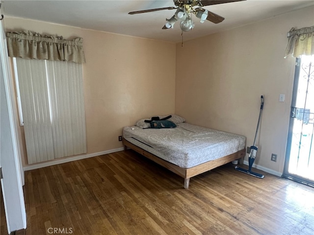 bedroom featuring wood finished floors, baseboards, and a ceiling fan