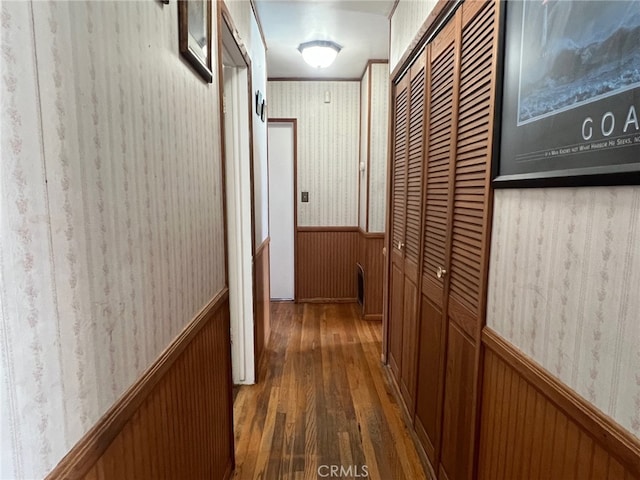 hall with wallpapered walls, dark wood-style flooring, and a wainscoted wall