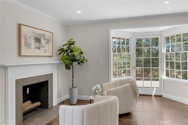 living area featuring healthy amount of natural light, baseboards, wood finished floors, crown molding, and recessed lighting