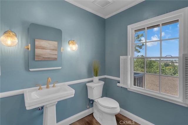 bathroom featuring baseboards, wood finished floors, toilet, and crown molding
