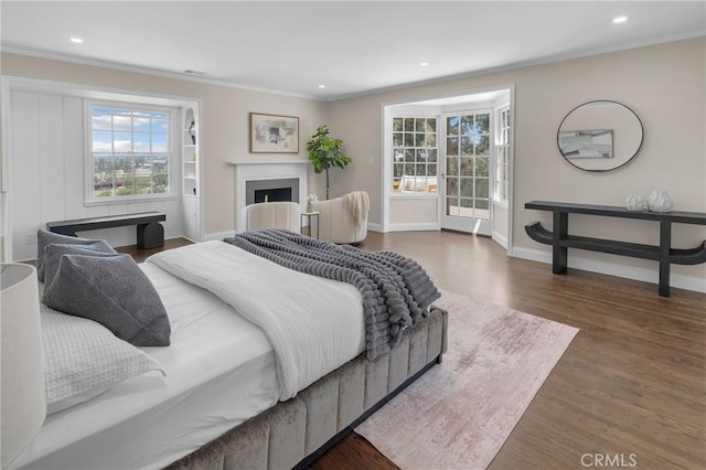 bedroom with multiple windows, crown molding, baseboards, wood finished floors, and recessed lighting