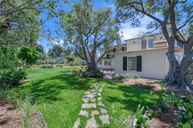 view of grassy yard with a balcony and a patio area