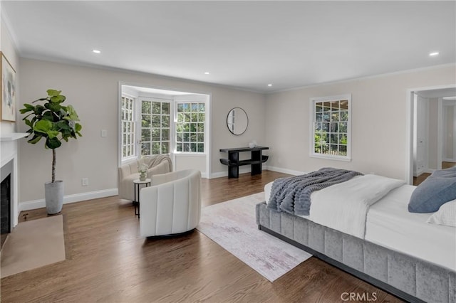 bedroom with multiple windows, crown molding, a fireplace, wood finished floors, and recessed lighting