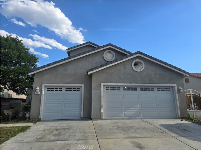 242 Spinnaker St, San Jacinto, CA 92583 - view of front of house featuring driveway, an attached garage, stucco siding, and a tiled roof