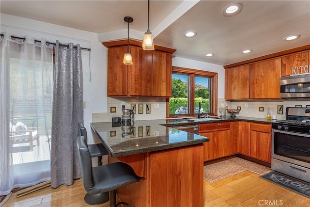 14048 Wagon Mound Rd, Rancho Cascades, CA 91342 - kitchen featuring appliances with stainless steel finishes, brown cabinets, a sink, a peninsula, and recessed lighting