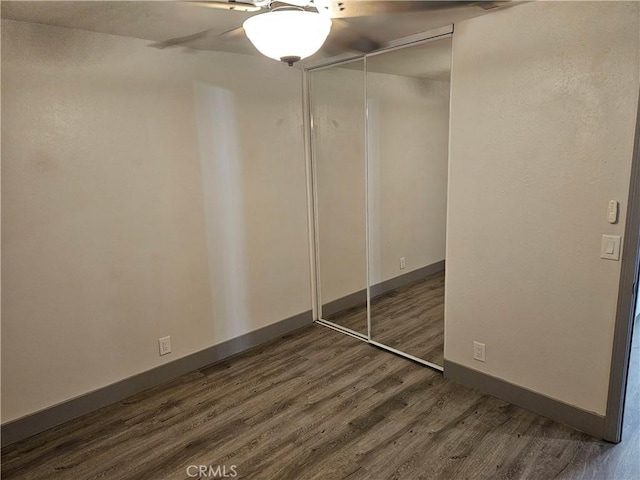 12860 Perris Blvd Unit D6, Moreno Valley, CA 92553 - unfurnished bedroom featuring dark wood-style flooring, a closet, baseboards, and a ceiling fan