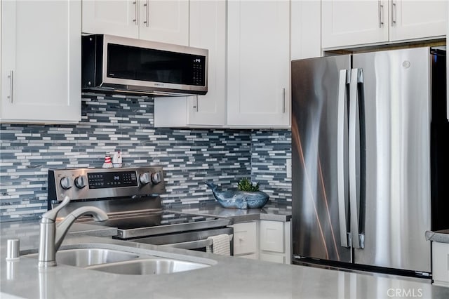 kitchen with stainless steel appliances, white cabinets, and backsplash