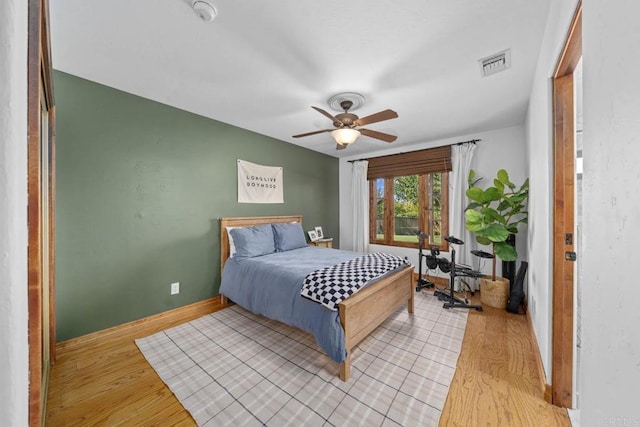 bedroom with light wood-style floors, baseboards, and ceiling fan