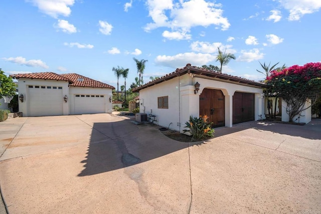 view of front facade featuring stucco siding, cooling unit, a garage, and a tile roof