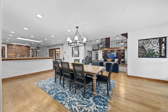 dining room featuring a chandelier, light wood-style floors, baseboards, and recessed lighting