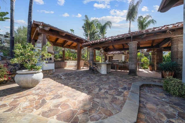 view of patio featuring exterior kitchen, a gazebo, and a bar