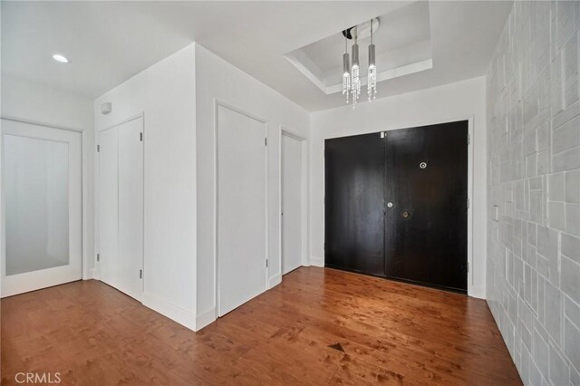 12218 Sarazen Pl, Granada Hills, CA 91344 - unfurnished bedroom featuring a tray ceiling, wood finished floors, and a chandelier