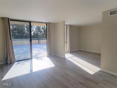 unfurnished room with baseboards, wood finished floors, and expansive windows