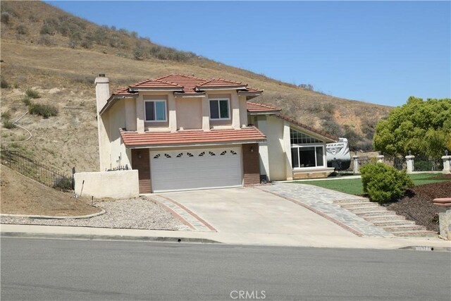 16971 Lakepointe Dr, Riverside, CA 92503 - mediterranean / spanish-style home featuring driveway, fence, a chimney, an attached garage, and stucco siding