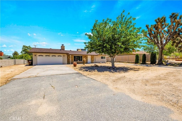 7599 Joshua Ln, Yucca Valley, CA 92284 - view of front of home with an attached garage, driveway, fence, and a chimney