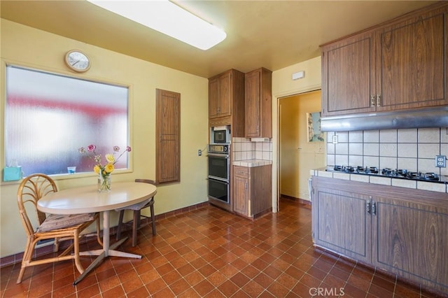 3784 Newton St, Torrance, CA 90505 - kitchen featuring black appliances, under cabinet range hood, decorative backsplash, baseboards, and brown cabinets