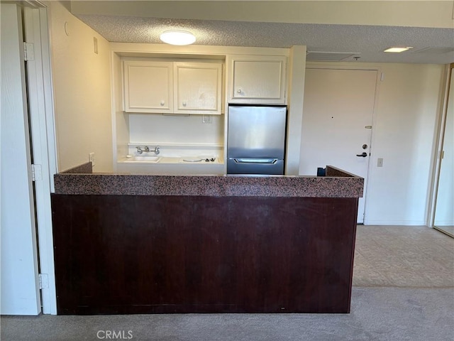 24055 Paseo Del Lago Unit 963, Laguna Woods, CA 92637 - kitchen featuring stainless steel refrigerator, a textured ceiling, white cabinetry, a peninsula, and carpet