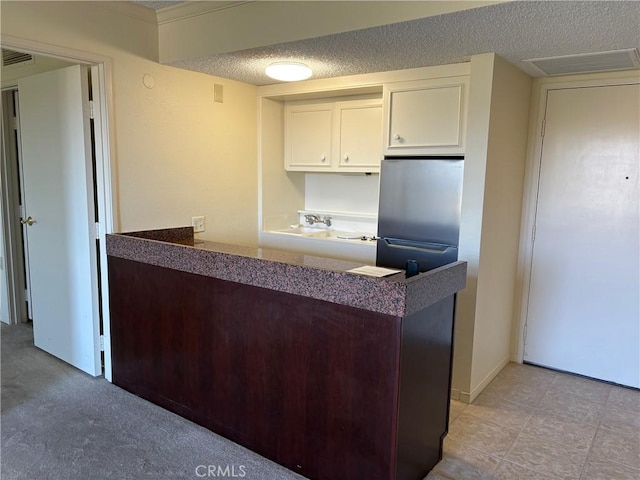 24055 Paseo Del Lago Unit 963, Laguna Woods, CA 92637 - kitchen featuring white cabinets, a textured ceiling, and a peninsula