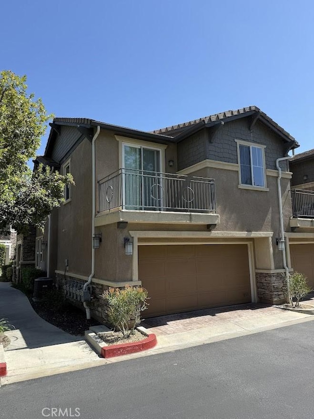 16722 Nicklaus Dr Unit 47, Rancho Cascades, CA 91342 - view of front facade featuring a balcony, stucco siding, a garage, and stone siding