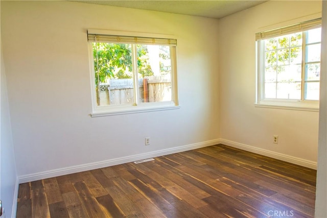 spare room featuring dark wood-type flooring and baseboards