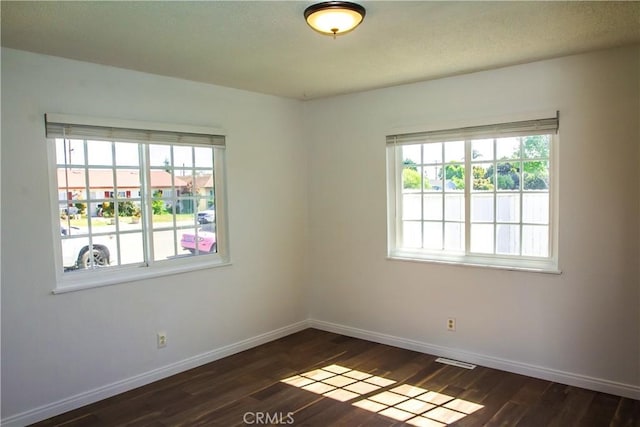 empty room with dark wood finished floors and baseboards