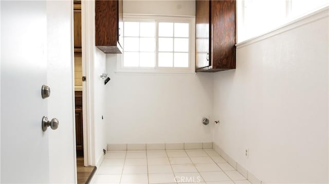 clothes washing area with cabinet space and baseboards