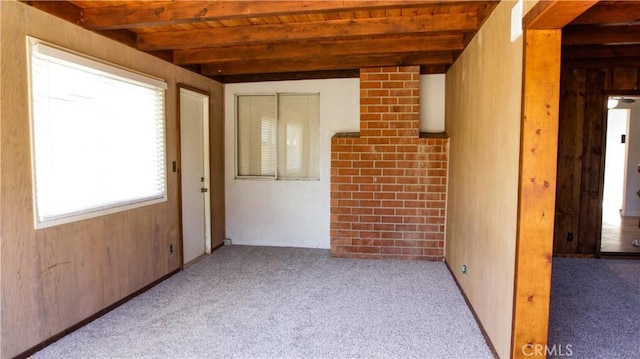 carpeted empty room with beam ceiling and wooden ceiling