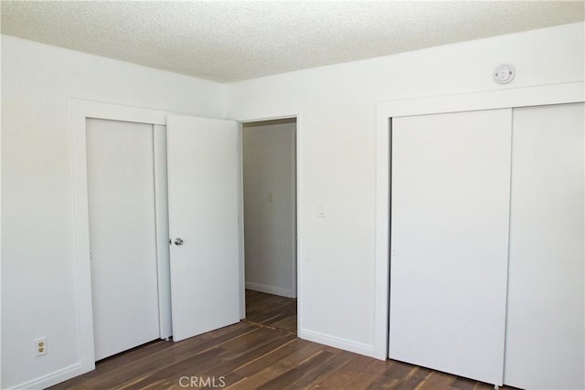 unfurnished bedroom with dark wood-type flooring, a textured ceiling, and baseboards