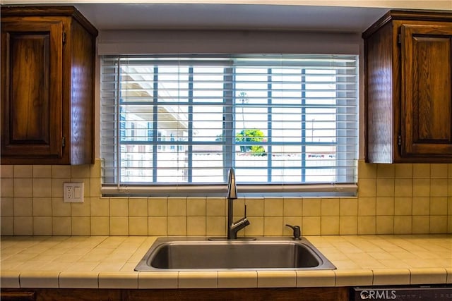 kitchen featuring a sink, dark brown cabinets, dishwashing machine, and tasteful backsplash