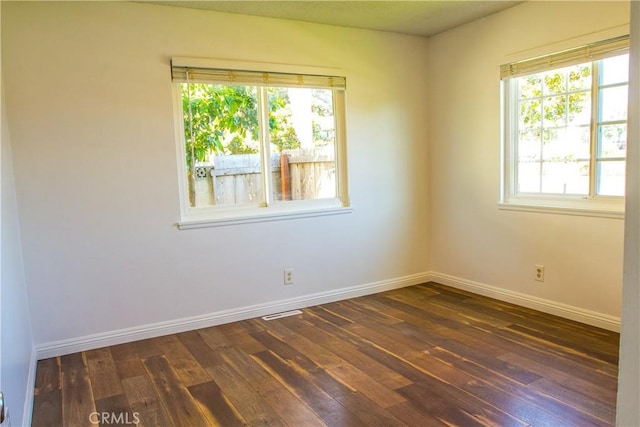 unfurnished room with dark wood finished floors and baseboards