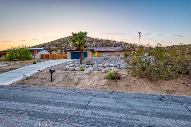 8244 Balsa Ave, Yucca Valley, CA 92284 - view of front of home with concrete driveway, a tile roof, an attached garage, and stucco siding