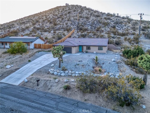 8244 Balsa Ave, Yucca Valley, CA 92284 - view of front of home with a mountain view, a garage, a tiled roof, concrete driveway, and stucco siding
