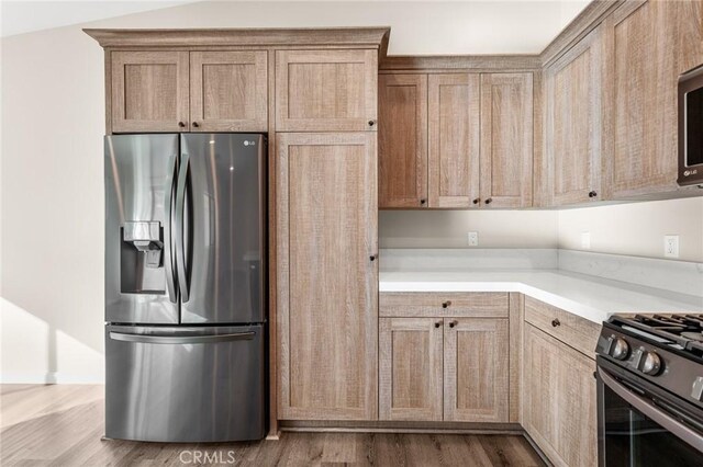 8244 Balsa Ave, Yucca Valley, CA 92284 - kitchen featuring stainless steel refrigerator with ice dispenser, light countertops, wood finished floors, and range with gas cooktop