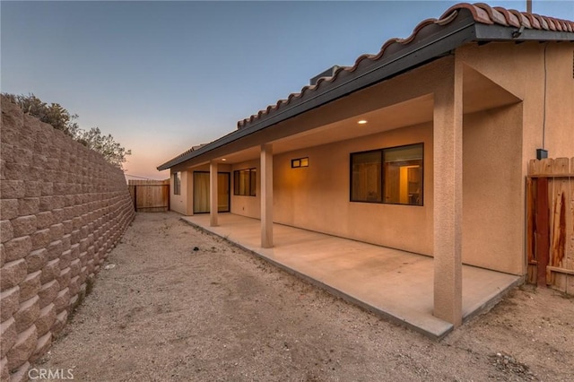 8244 Balsa Ave, Yucca Valley, CA 92284 - back of property at dusk with a patio, stucco siding, a fenced backyard, and a tile roof