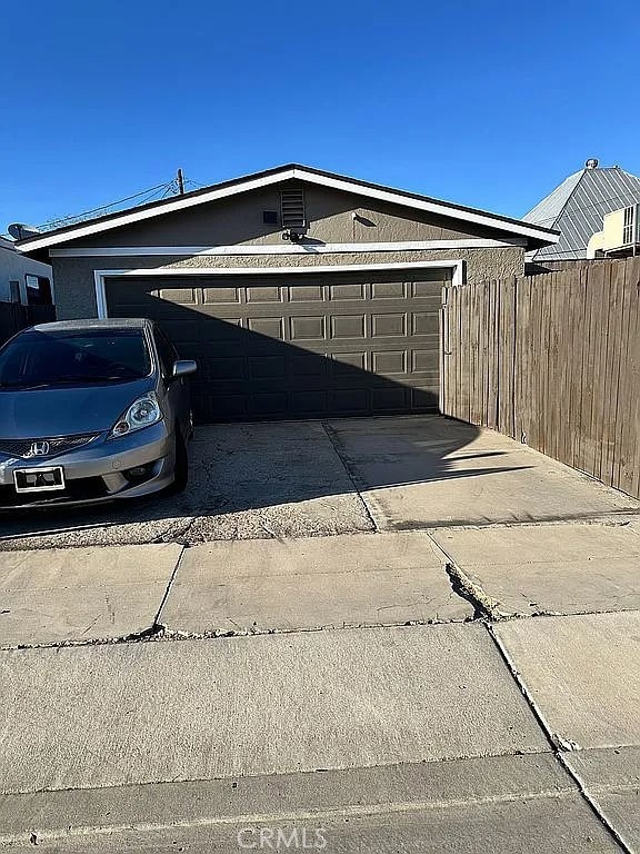 garage featuring driveway and fence