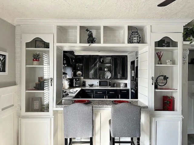 bar area featuring a textured ceiling, crown molding, a sink, and built in shelves