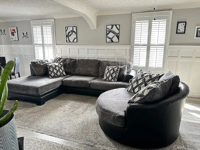 living room featuring a textured ceiling, a wainscoted wall, and a decorative wall