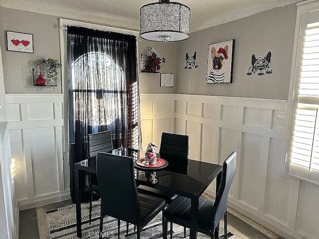 dining space featuring a decorative wall, a wainscoted wall, and plenty of natural light