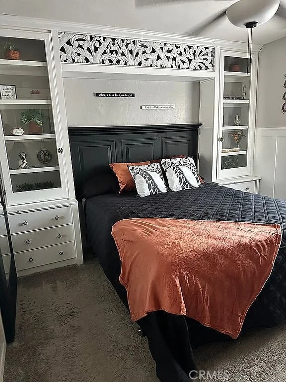 carpeted bedroom featuring a wainscoted wall