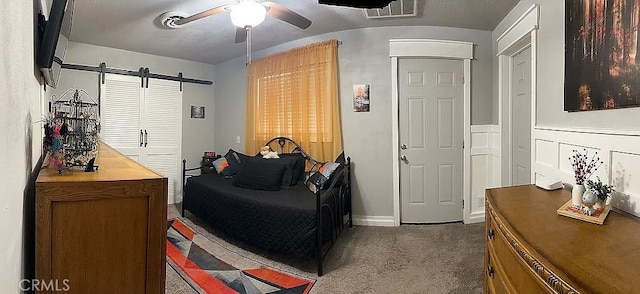bedroom featuring carpet floors, a barn door, and a ceiling fan