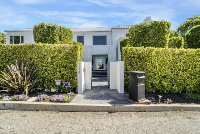 1116 Linda Flora Dr, Los Angeles, CA 90049 - view of front of home with a standing seam roof, stucco siding, metal roof, and a chimney