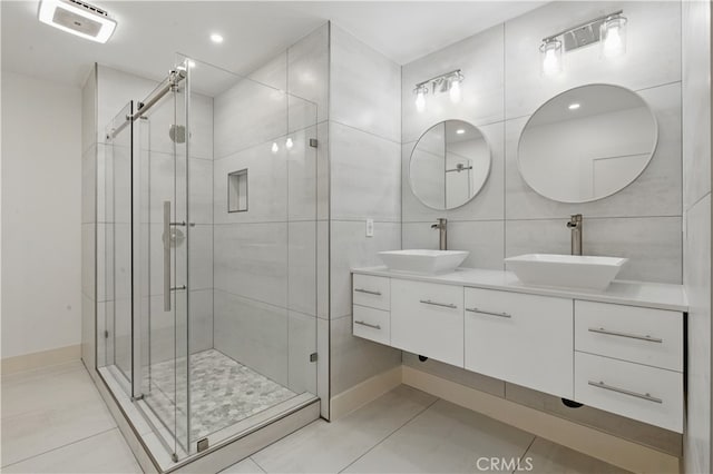 bathroom with a stall shower, double vanity, tile patterned floors, and baseboards