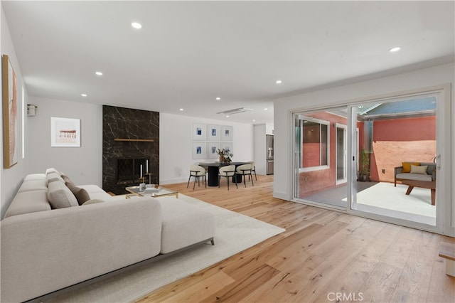 living area with recessed lighting, light wood finished floors, and a premium fireplace