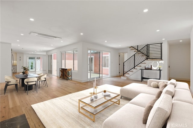 living area featuring stairs, light wood-style floors, recessed lighting, and baseboards