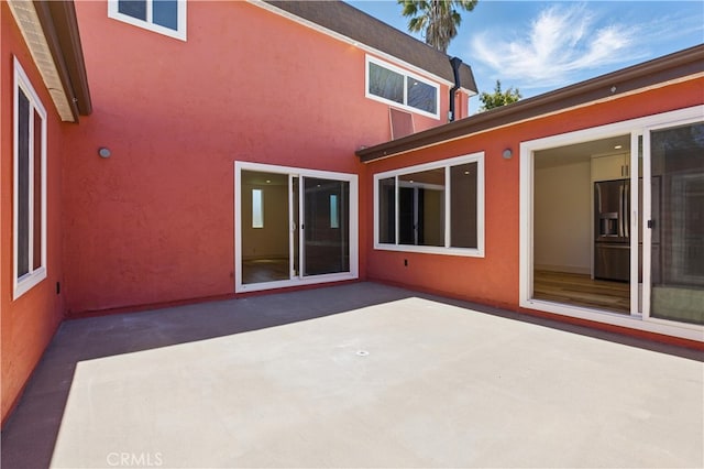 rear view of house with a patio and stucco siding