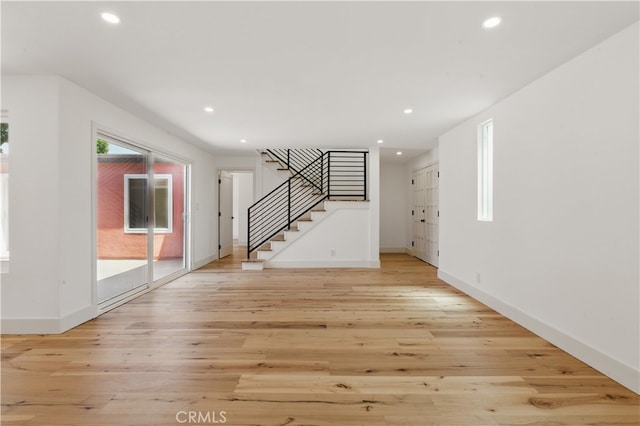unfurnished living room featuring stairway, recessed lighting, light wood-type flooring, and baseboards