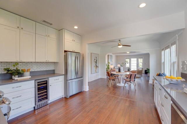 487678 34th St, San Diego, CA 92116 - kitchen with freestanding refrigerator, wine cooler, arched walkways, backsplash, and white cabinetry