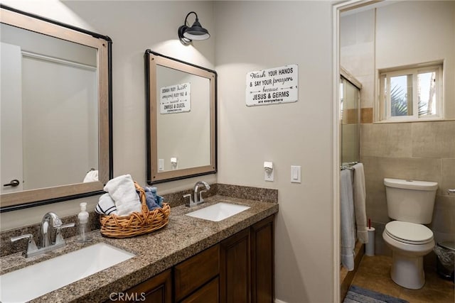 full bath featuring double vanity, a shower with shower door, toilet, and tile patterned flooring